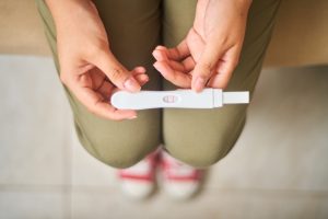 A woman looking at a positive pregnancy test in the bathroom after seeing a fertility specialist